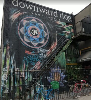 Exterior of Downward Dog Yoga Centre in Toronto s Ontario with a beautiful graffiti on the side of building entrance.
